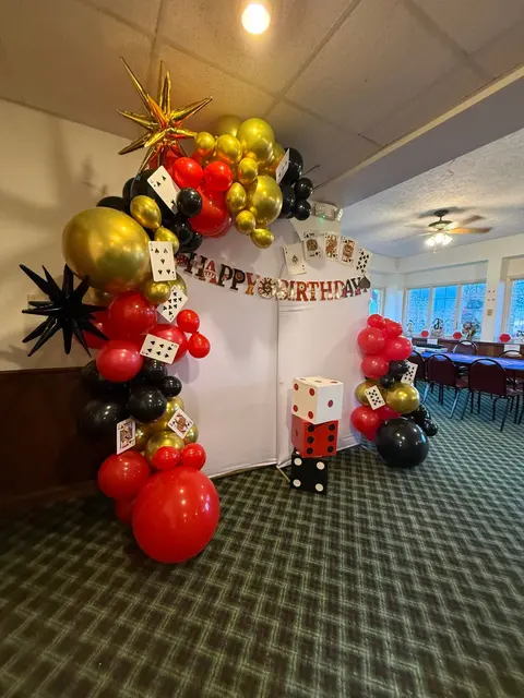 Red, black, and gold casino-themed balloon arch in the event room