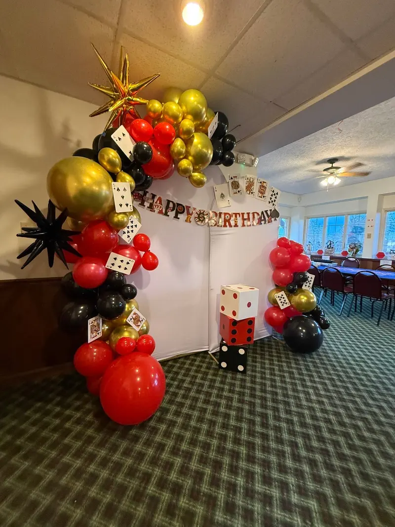 Red, black, and gold casino-themed balloon arch in the event room
