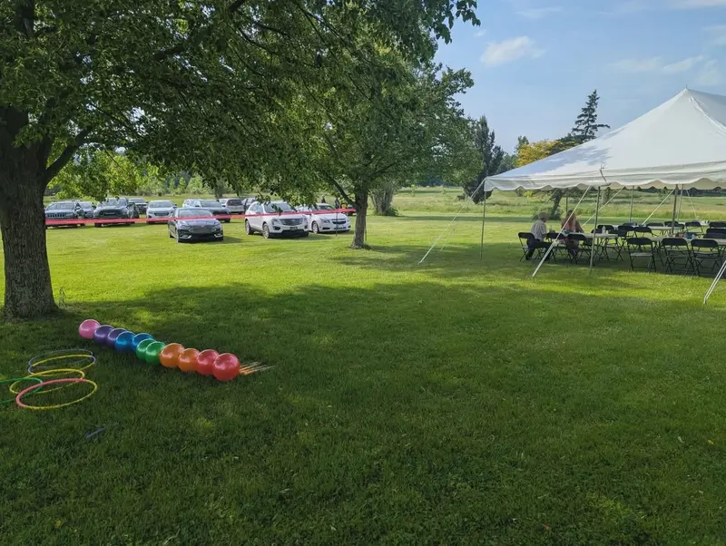 Spacious venue lawn with an outdoor event tent and guest parking beyond