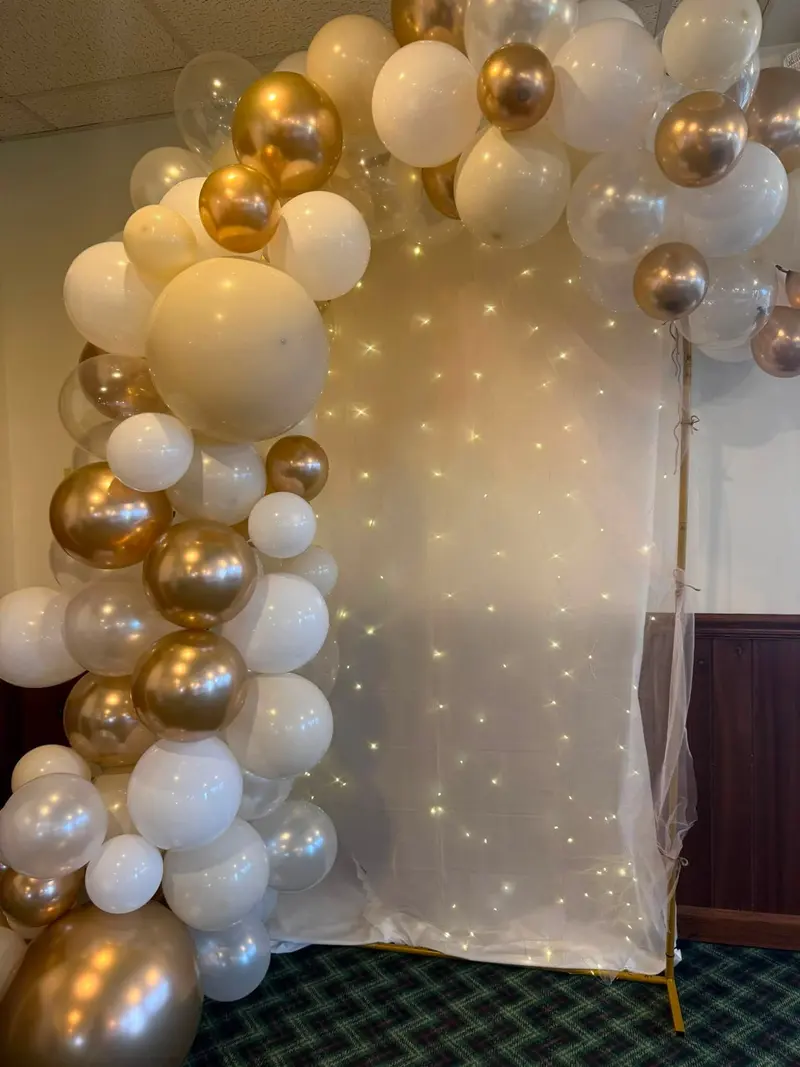 White and gold balloon arch glowing against a lighted event backdrop