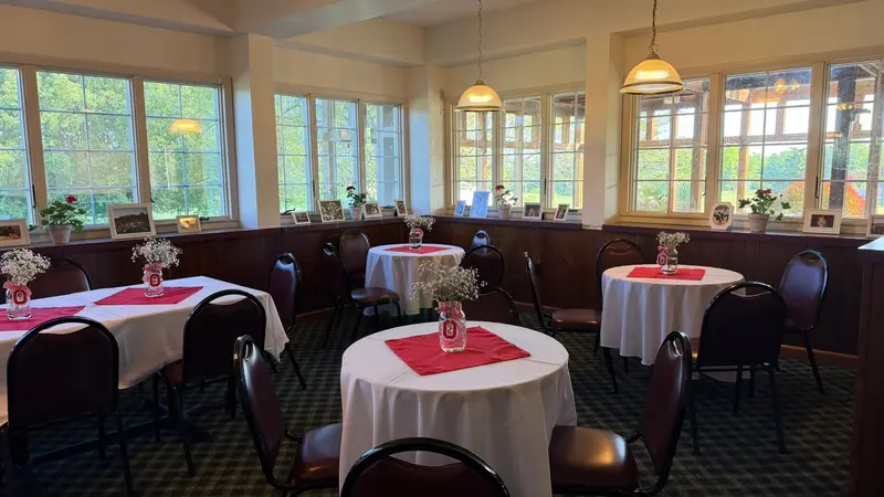 Round tables with red accents in the bright window-lined event room