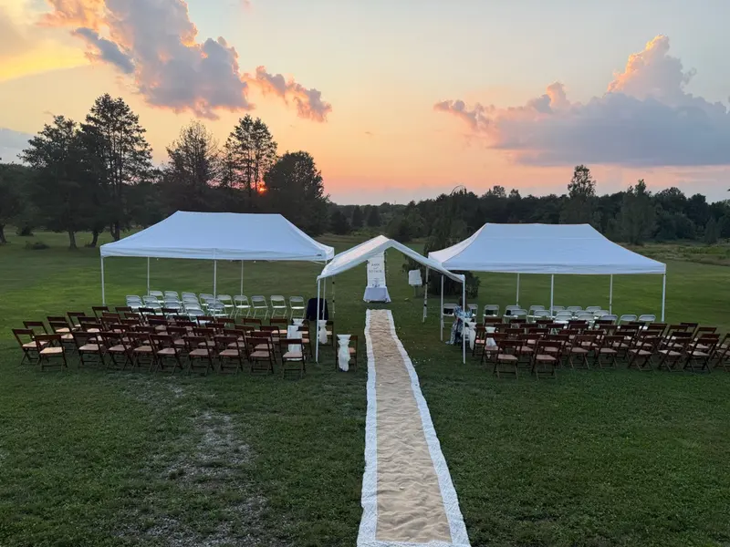 Sunset outdoor wedding ceremony with tented seating and a fabric aisle