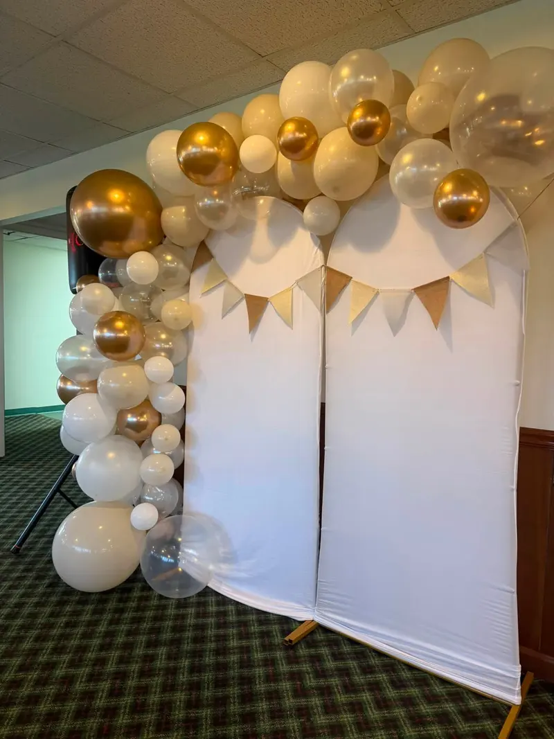 White and gold balloon garland framing a celebration backdrop
