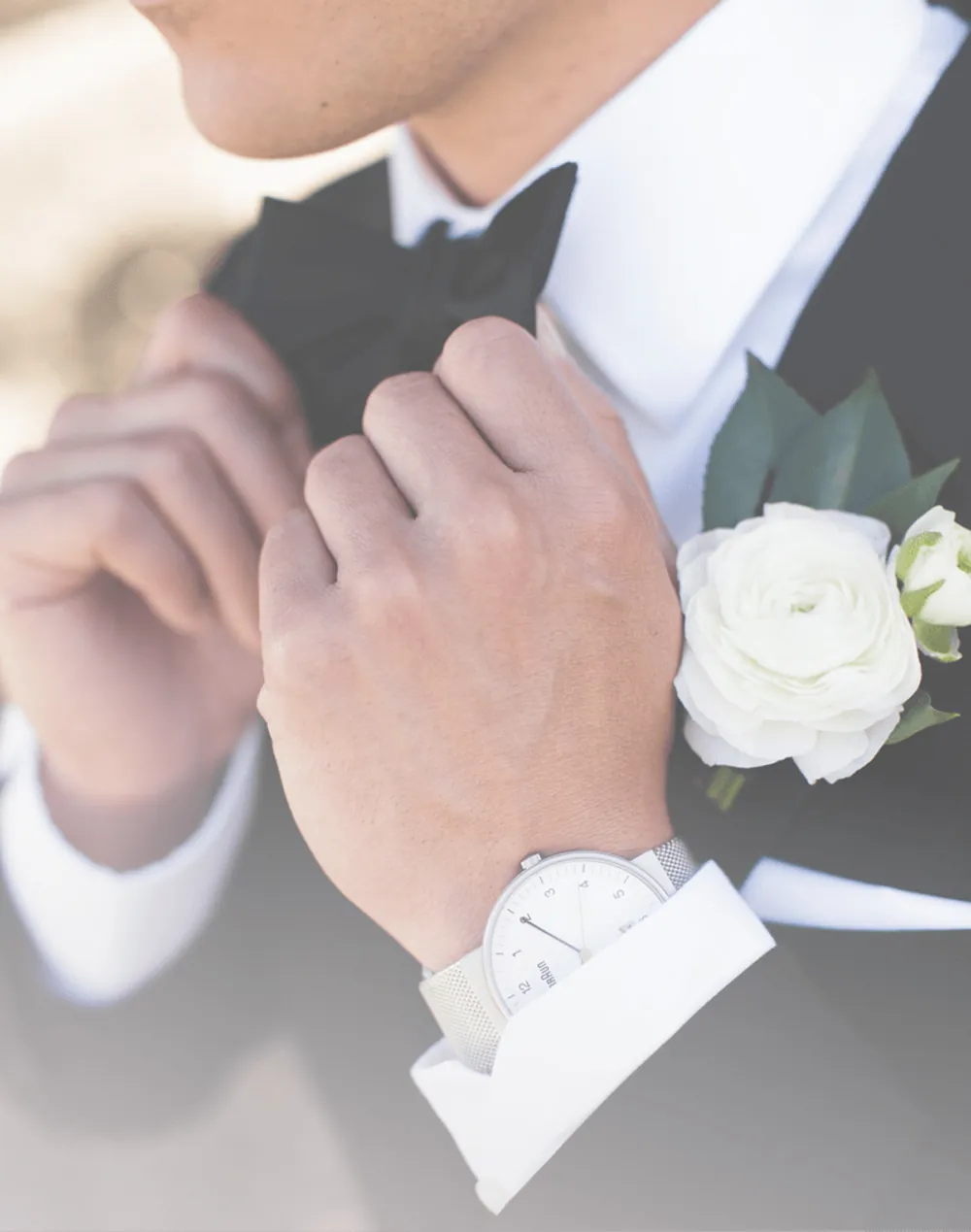 Groom adjusting his bow tie and boutonniere